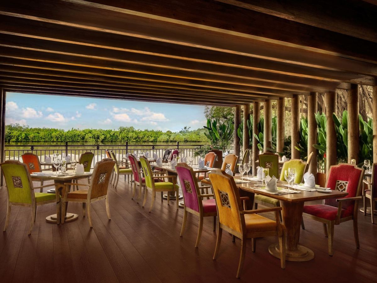 Open-sided riverside dining room with colourful chairs and long views over the water