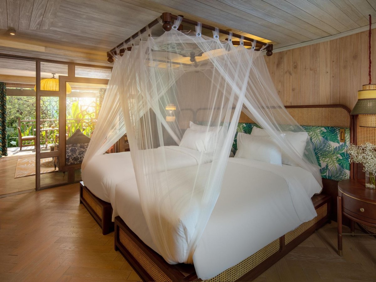 Two single beds under white mosquito-net canopies in a timber-clad bedroom