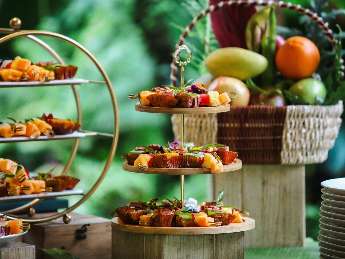 Tiered display of breakfast dishes and fruit on wooden stands in a garden setting