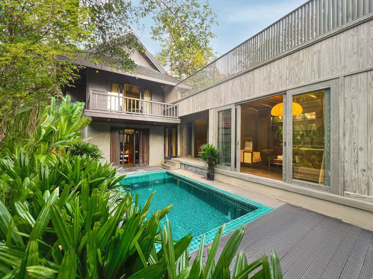 Two-storey timber villa beside a turquoise private pool in dense tropical planting