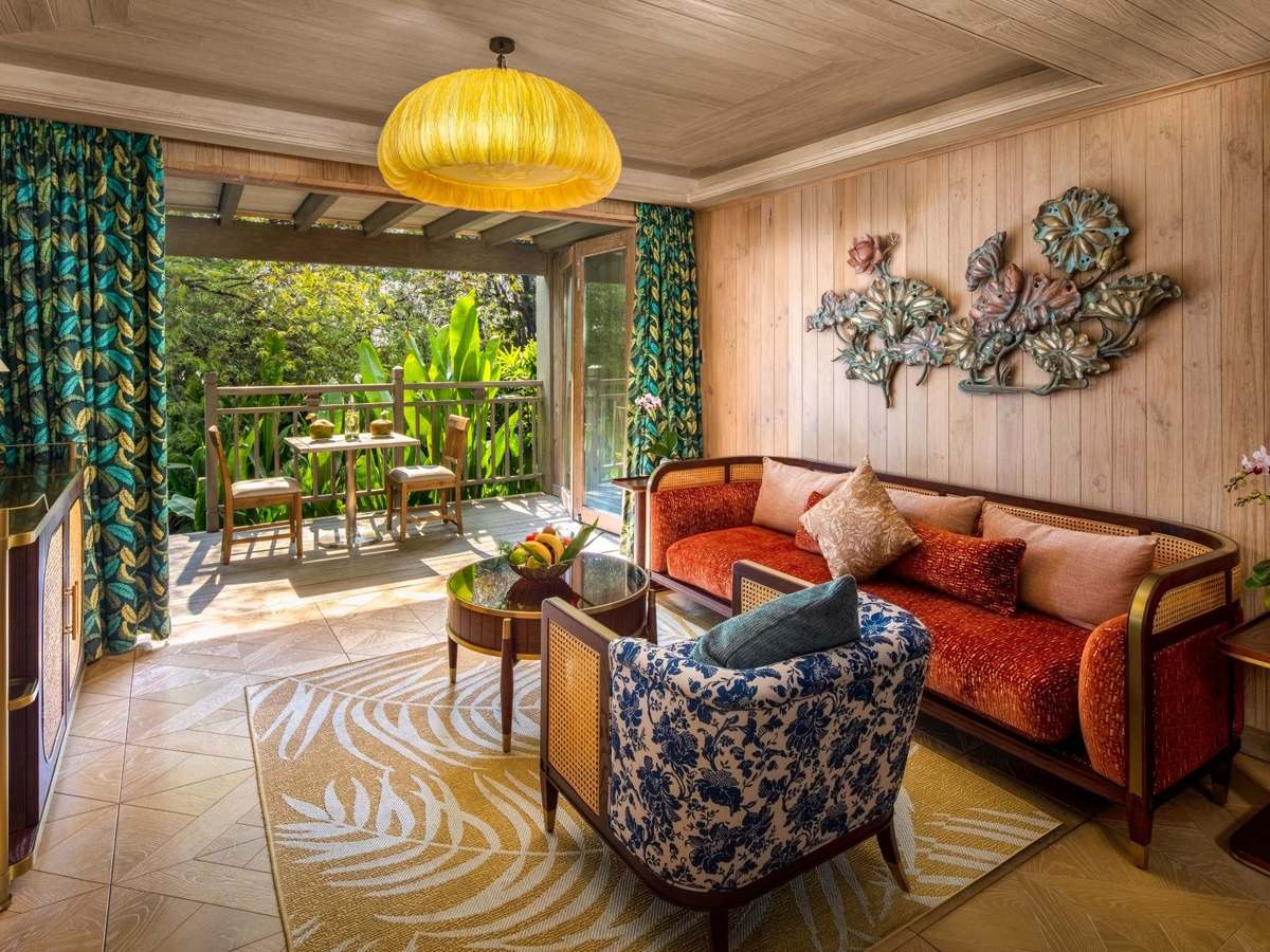 Living room with a red sofa, patterned armchairs and folding doors open to a garden terrace