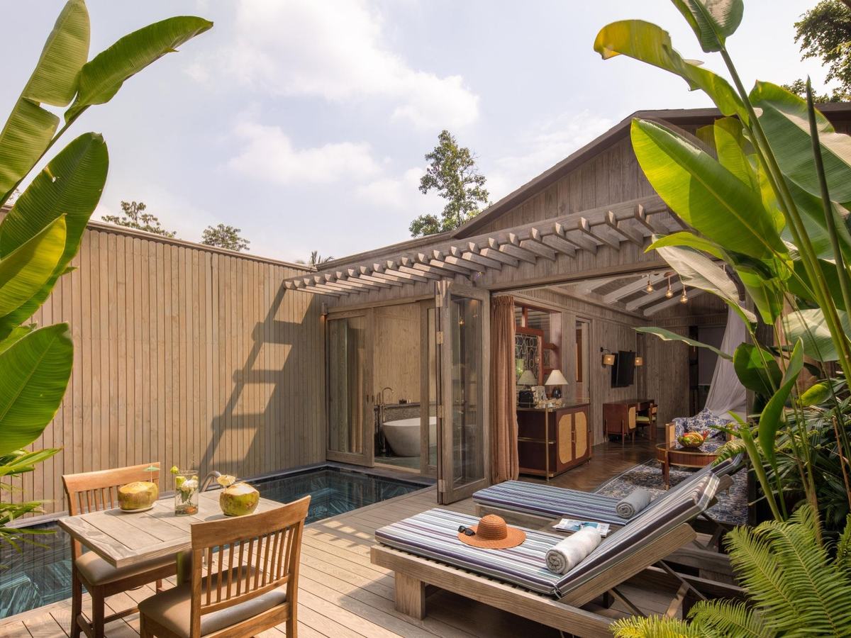 Private plunge pool and teak sun deck outside a timber villa among banana plants